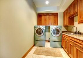 Rectangle laundry room with wooden cabinets and modern shiny appliances